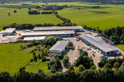 Luftaufnahme landwirtschaftlicher Betrieb; Hallen und Lagerflächen; Fahrzeuge auf dem Hof; umgeben von grünen Feldern