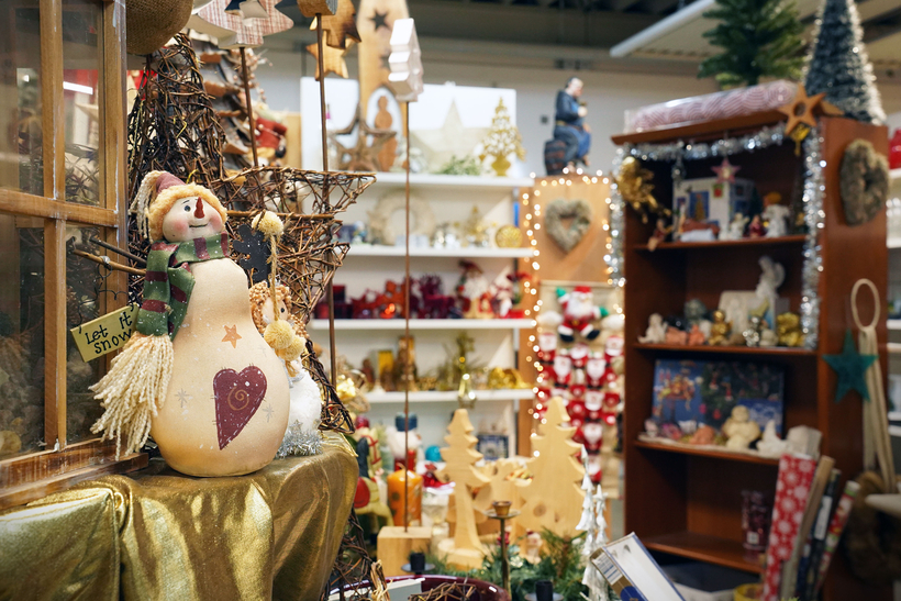 Auf dem Bild sind festliche Dekorationen und Weihnachtsartikel in einem Geschäft zu sehen, darunter ein Schneemann und verschiedene weihnachtliche Accessoires.