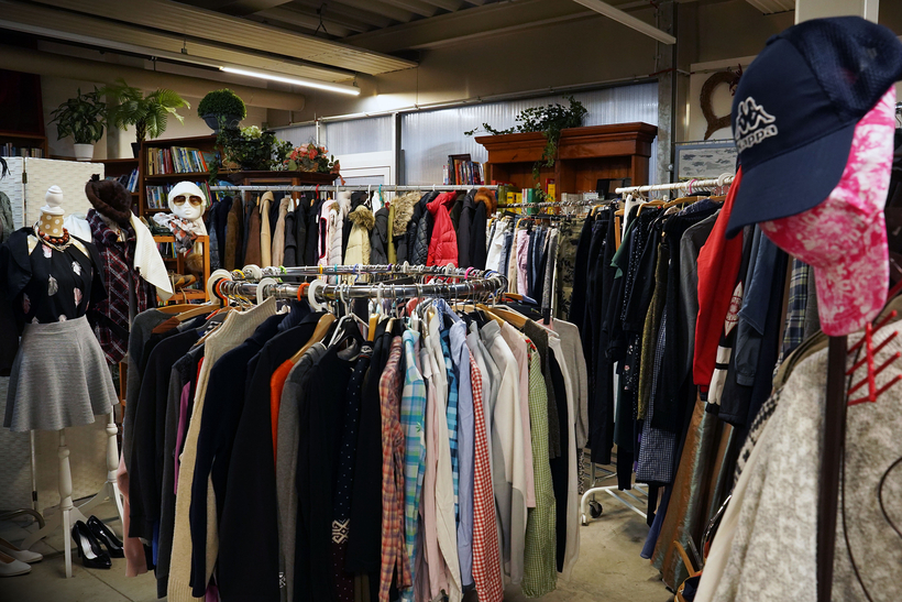 Auf dem Bild ist ein Second-Hand-Laden mit einer Vielzahl von Bekleidungsstücken und Accessoires zu sehen.