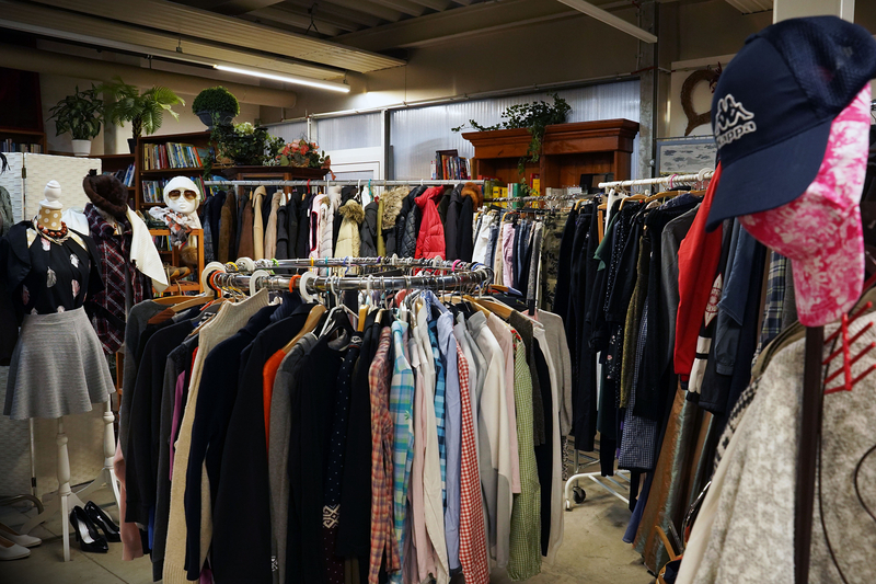 Auf dem Bild ist ein Second-Hand-Laden mit einer Vielzahl von Bekleidungsstücken und Accessoires zu sehen.