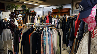 Auf dem Bild ist ein Second-Hand-Laden mit einer Vielzahl von Bekleidungsstücken und Accessoires zu sehen.