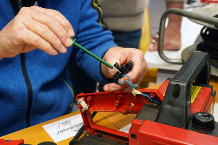 Auf dem Bild ist eine Person zu sehen, die mit einem Schraubendreher an einem elektrischen Gerät arbeitet.