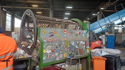 Das Bild zeigt eine recyclinganlage mit einem großen, mit Aufklebern bedeckten Maschinenraum, in dem Abfälle verarbeitet werden.