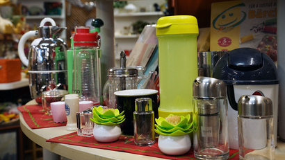 Auf dem Bild sind verschiedene Küchenutensilien und -gefäße, darunter Kannen, Gläser und Gewürzbehälter, auf einem Tisch angeordnet.