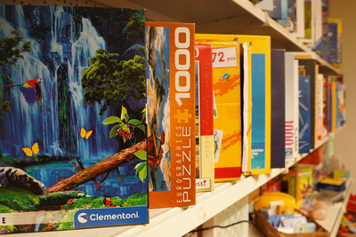 Auf dem Bild sind verschiedene Puzzle-Schachteln auf einem Regal zu sehen.