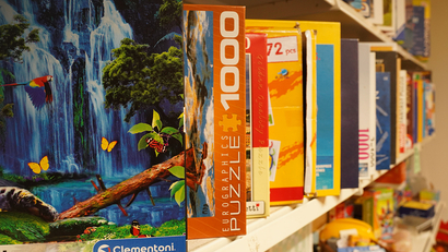 Auf dem Bild sind verschiedene Puzzle-Schachteln auf einem Regal zu sehen.